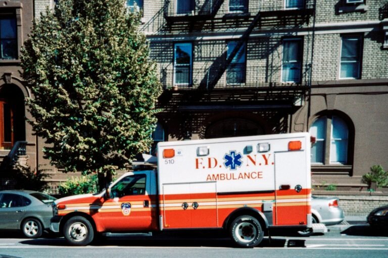 white and red ambulance van parked near green trees during daytime