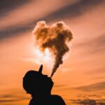 silhouette of man vaping during sunset