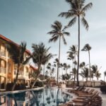 brown wooden lounge chairs near pool surrounded by palm trees, celebration