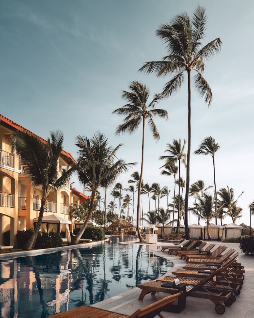 brown wooden lounge chairs near pool surrounded by palm trees, celebration
