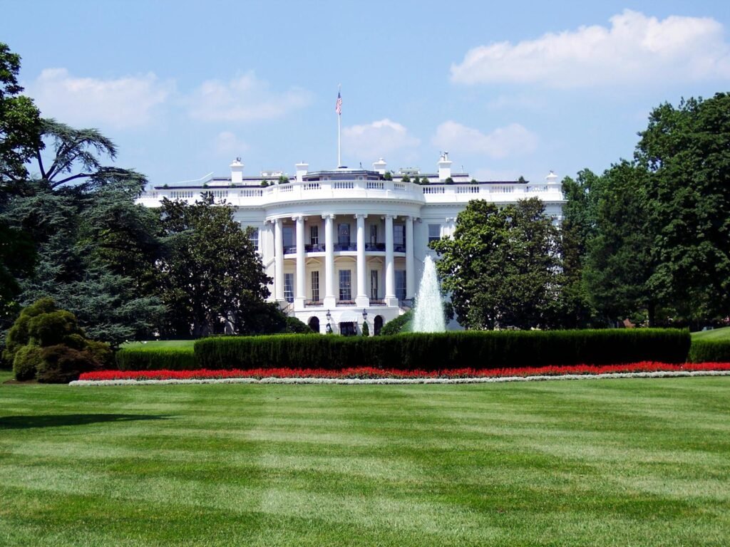 Ellison Leads Coalition of Attorneys General Condemning Trump’s Attacks on Nonprofit Freedoms 1 Iconic view of the White House with lush gardens and a central fountain on a sunny day.