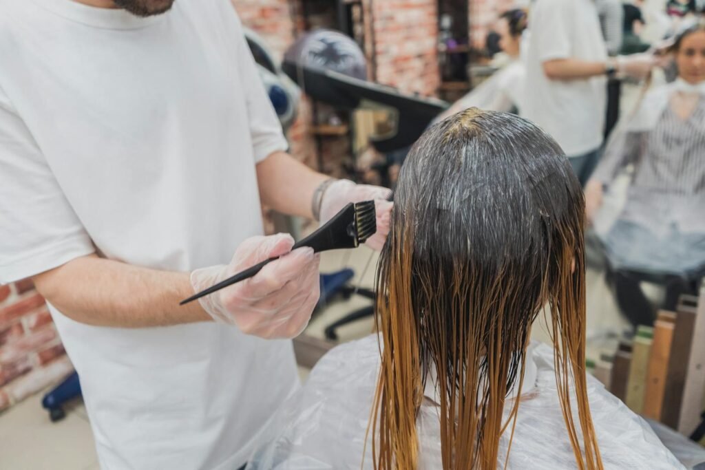 Hair Relaxer Lawsuits Surge Amid Cancer Risk Concerns: Thousands of Women File Claims Against Major Brands 1 Hair coloring process in a salon, showcasing stylist applying color to client's hair.