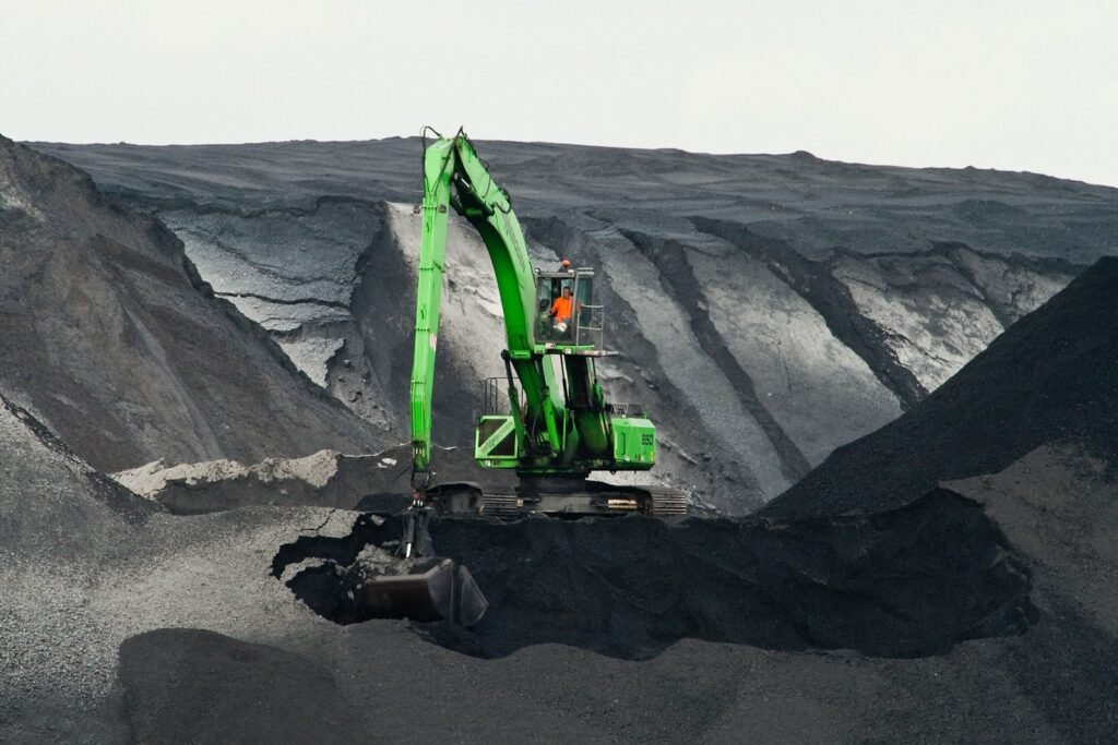 Silica Dust Rule Delayed Again, Advocates Say Miners' Lives at Risk 1 green backhoe digging hole in the middle of mountain