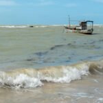 A lone fishing boat floats on the choppy waters off the coast of Arraial d'Ajuda, Bahia, Brazil.