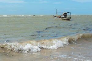 A lone fishing boat floats on the choppy waters off the coast of Arraial d'Ajuda, Bahia, Brazil.