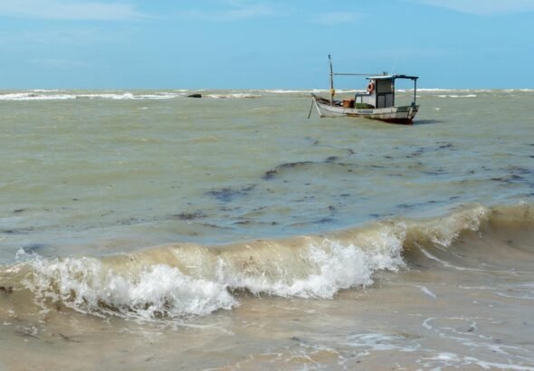 A lone fishing boat floats on the choppy waters off the coast of Arraial d'Ajuda, Bahia, Brazil.
