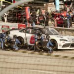 Intense pit stop during a car race in Miami, featuring teamwork and precision.