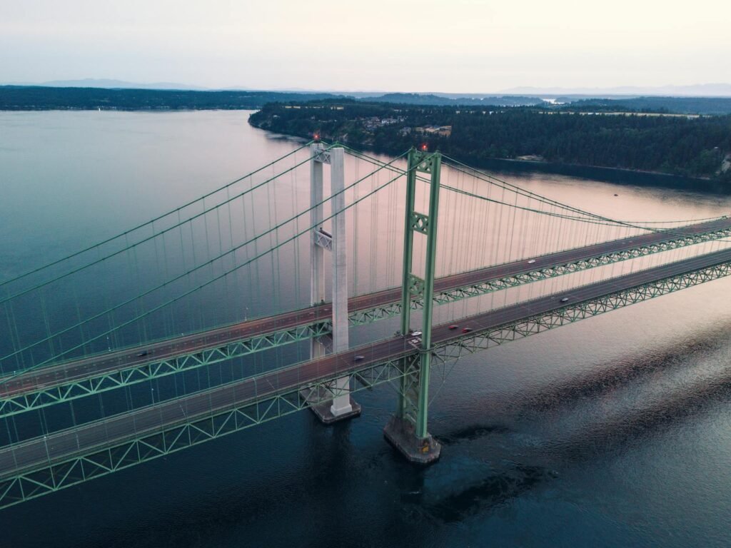 Pierce County Turns Up the Glow: A Guide to the Region’s Holiday Magic 1 Aerial view of Tacoma Narrows Bridge spanning over serene waters at sunset.