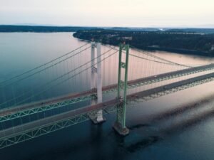 Aerial view of Tacoma Narrows Bridge spanning over serene waters at sunset.