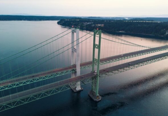 Aerial view of Tacoma Narrows Bridge spanning over serene waters at sunset.