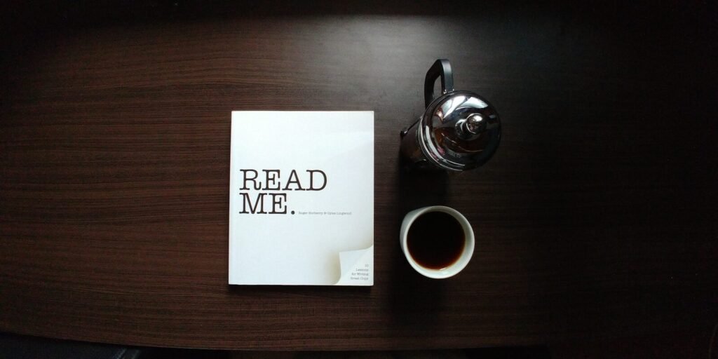 flat-lay photo of Read Me. book beside cup and silver mug on table. Press Release, guest post, sponsored posts, classified listing