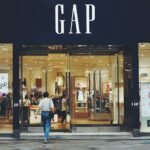 person in white shirt and blue jeans walking inside GAP store, gap