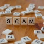 Scam spelled with scrabbles on a wooden table, schemes