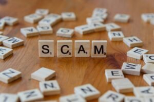 Scam spelled with scrabbles on a wooden table, schemes