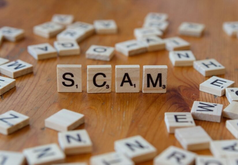 Scam spelled with scrabbles on a wooden table, schemes, ftc