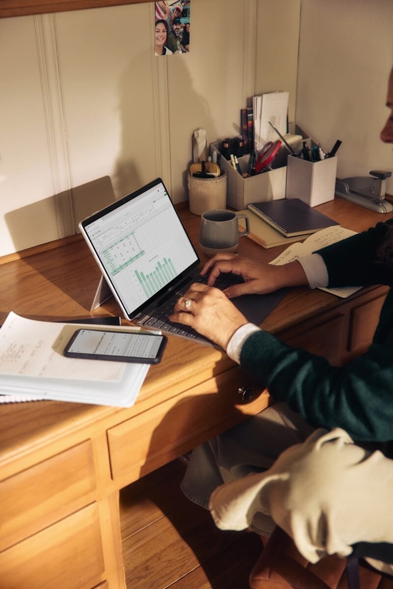 Person working on laptop at a wooden desk. support